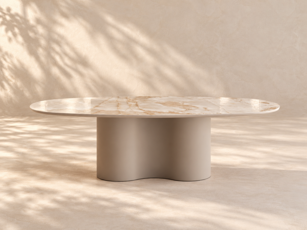 Stół Fortuna z kolekcji Glam Vena Design: owalny blat ze spieku kwarcowego Reve Noisette poler na falistej podstawie ze stali malowanej proszkowo w kolorze Taupe, w ciepłym świetle dnia.