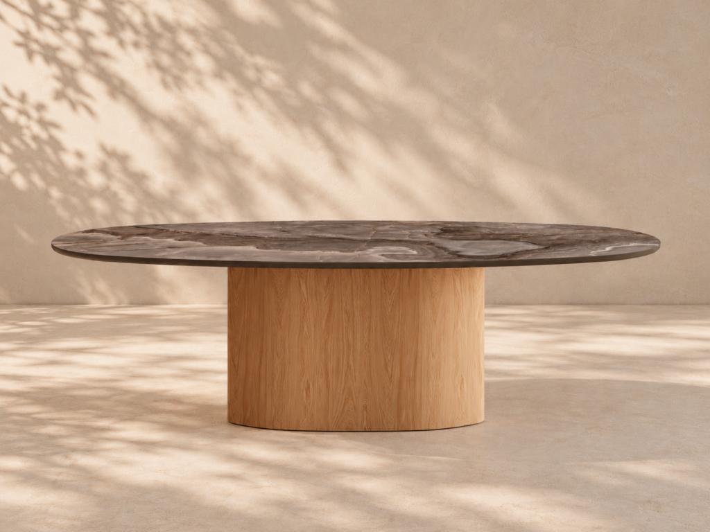 Stół Elisse z kolekcji Organica Vena Design: owalny blat ze spieku kwarcowego Reve Choco o ciemnym, onyksowym rysunku na owalnej kolumnie z forniru dębowego, w ciepłym świetle dnia.