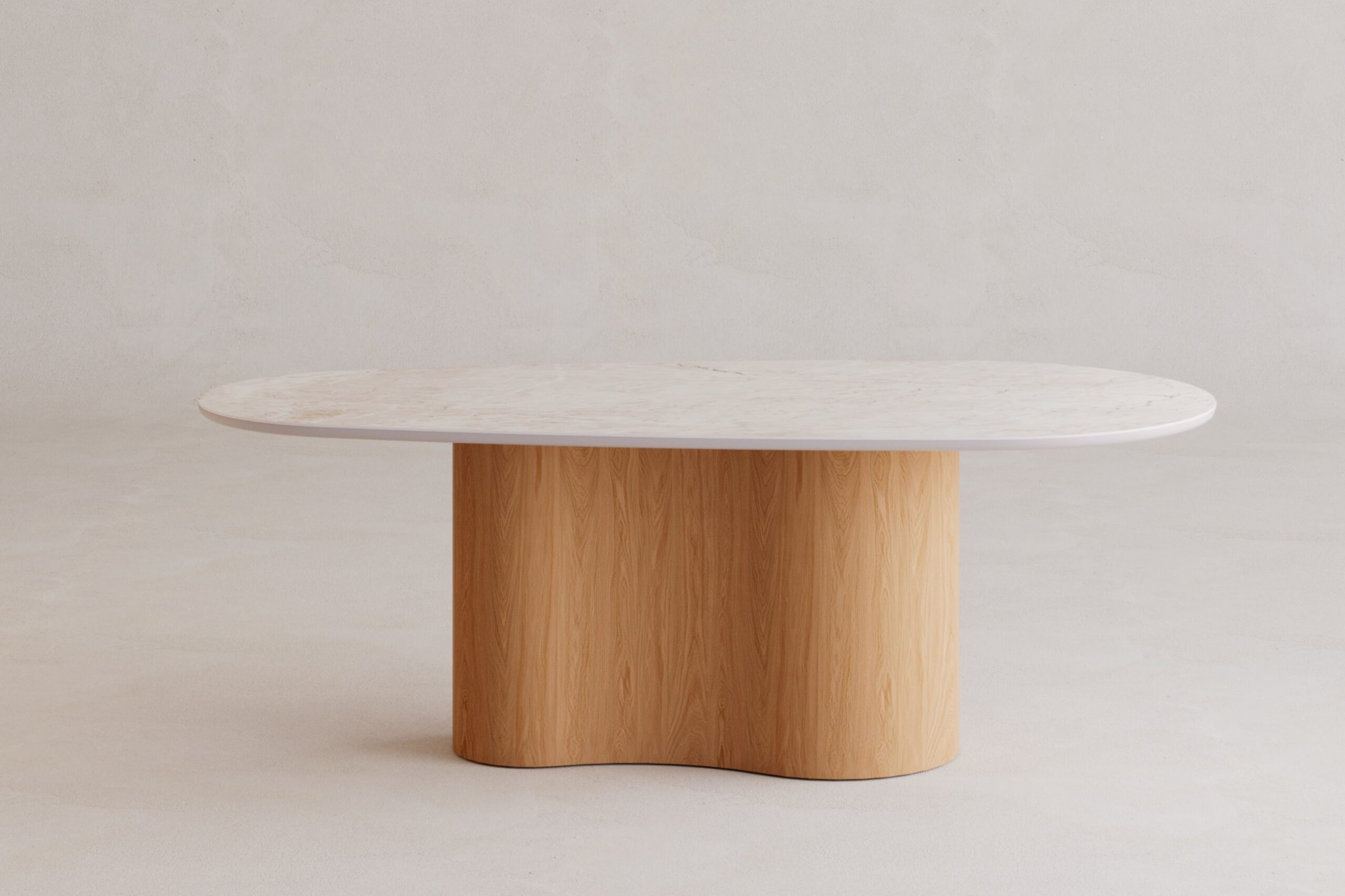 Stół Fortuna z kolekcji Organica Vena Design: owalny blat ze spieku kwarcowego Marble Mahal w kremowej bieli ze złotymi żyłkami, na centralnej, falistej podstawie z forniru dębowego w wybarwieniu Natura, ujęcie z przodu na tle jasnego tynku.